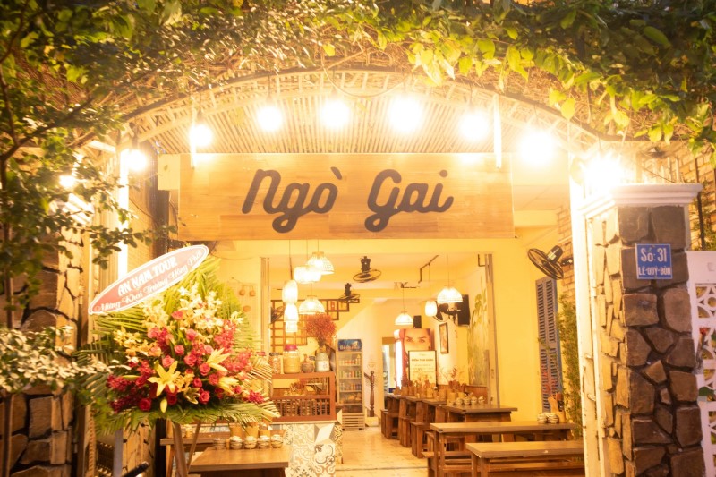 the interior of ngo gai restaurant filled with wooden tables and chairs and cozy lights