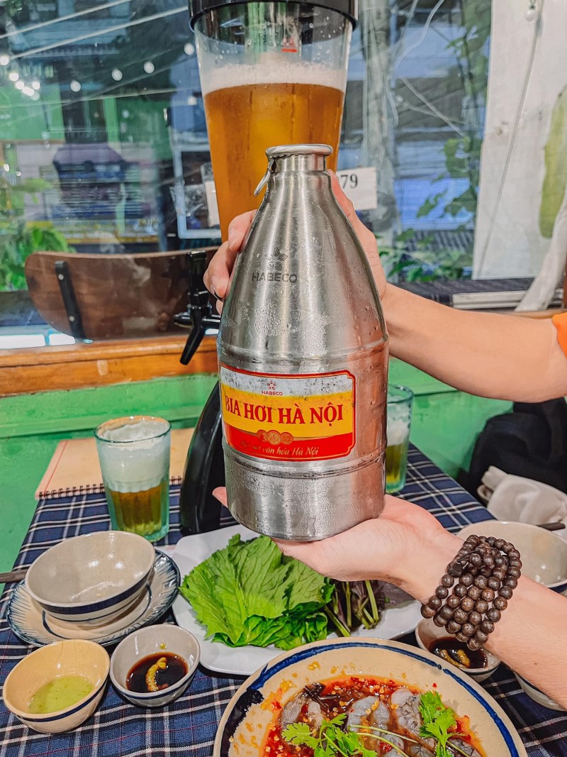 a man holding a tower of Hanoi draft beer served at Nha Trang Co Do 86 draft bee