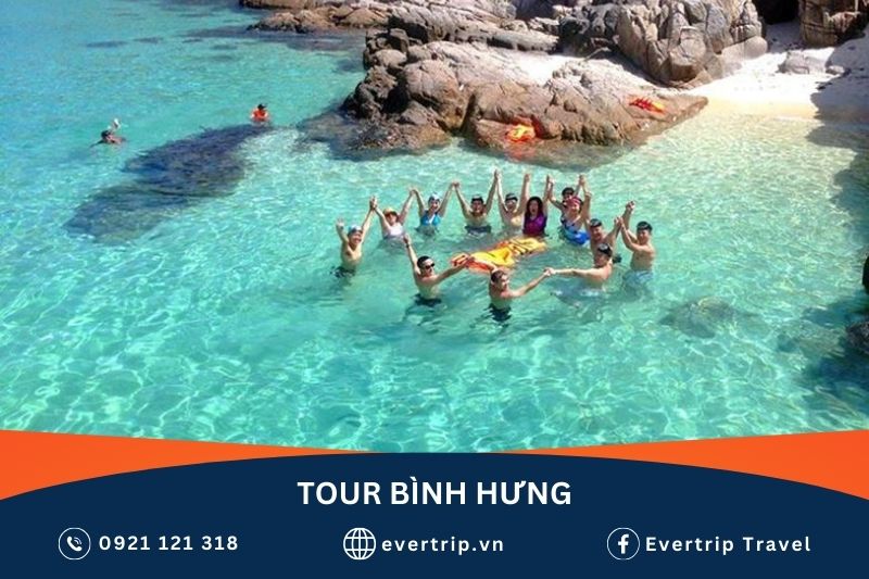 nhóm bạn tắm biển tại bãi kinh trong tour đi bình hưng, phía sau là hai người đang mặc áo phao bơi lội trong làn nước trong vắt