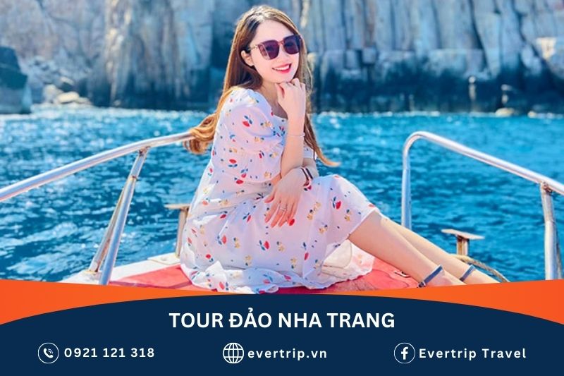 cô gái ngồi trên mũi cano chụp hình cùng biển và vách núi sau lưng